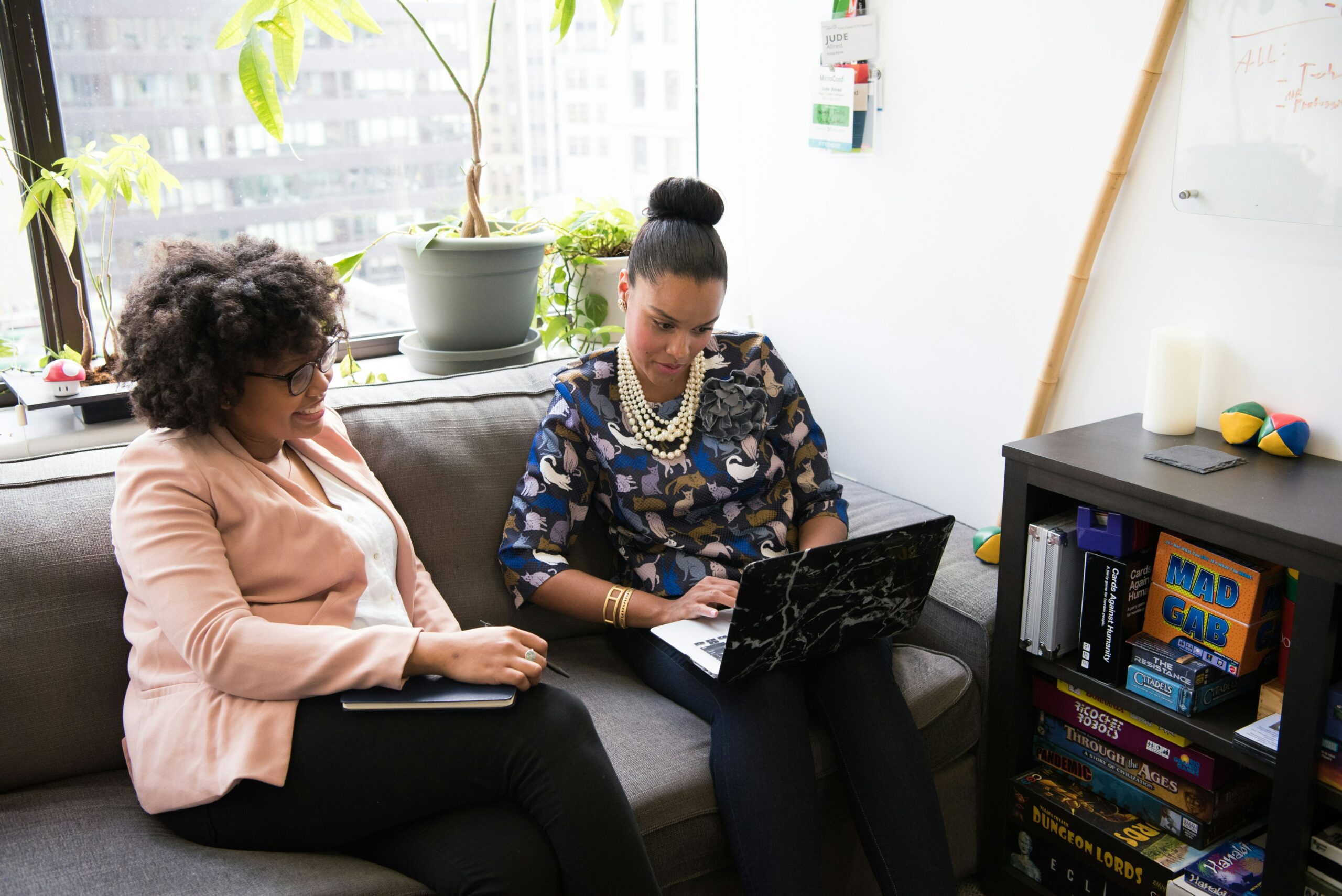 Two people sitting together on a sofa, looking at a laptop.