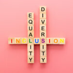 Scrabble letters on a pink background. Vertically, equality and diversity are spelled out; they intersect with inclusion which is laid out horizontally.